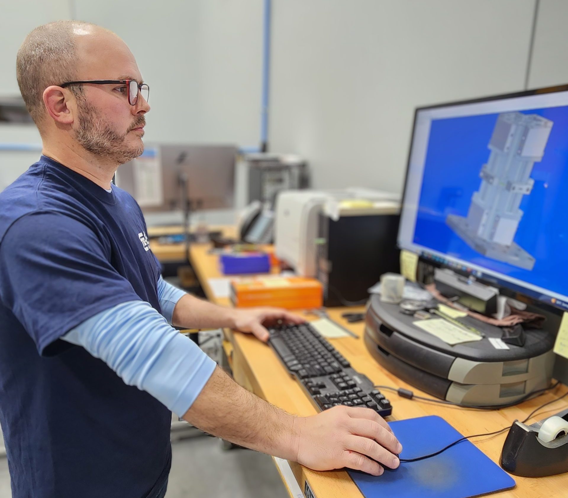 a man wearing a blue shirt looking at CAD drawings